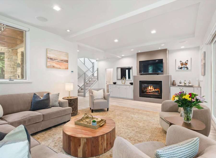 Experience modern living in this beautifully appointed living room, featuring a cozy fireplace and a large television for entertainment.