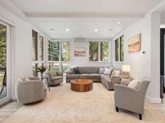 Experience modern living in this spacious living room, featuring a large sectional sofa and comfortable armchairs perfect for relaxation.