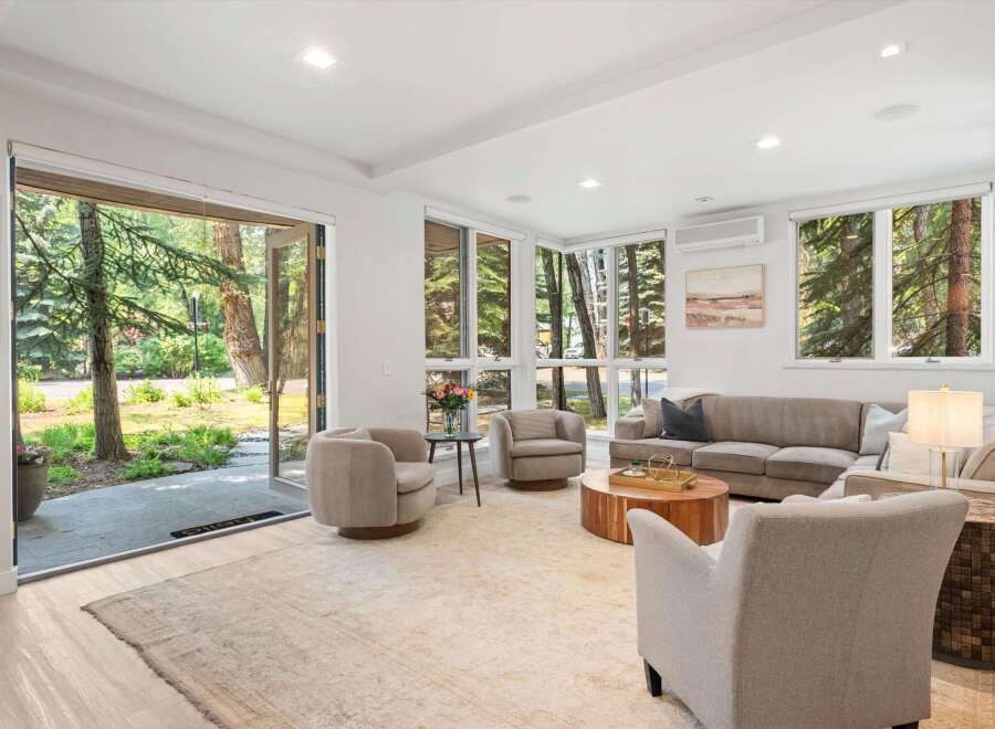 Step into this inviting living room, bathed in natural light from large windows overlooking a serene wooded landscape.