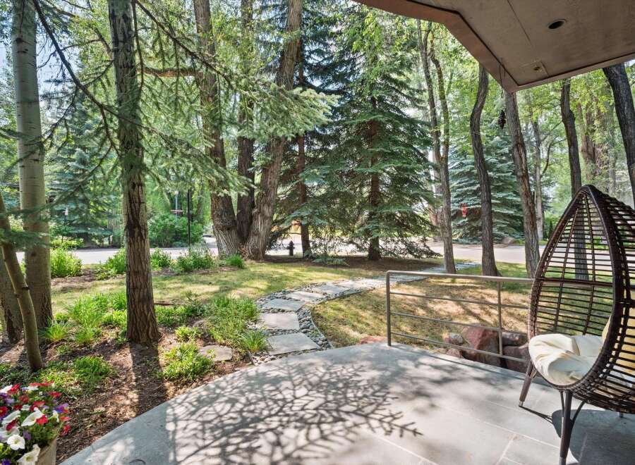 Enjoy the serene ambiance of this property's outdoor living space, featuring a charming stone pathway winding through lush greenery and mature trees.