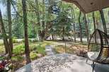 Enjoy the serene ambiance of this property's outdoor living space, featuring a charming stone pathway winding through lush greenery and mature trees.