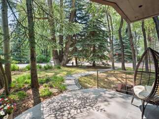 Enjoy the serene ambiance of this property's outdoor living space, featuring a charming stone pathway winding through lush greenery and mature trees.