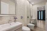 Experience modern luxury in this stunning bathroom, featuring a sleek vanity with a waterfall faucet and a unique textured stone accent wall.