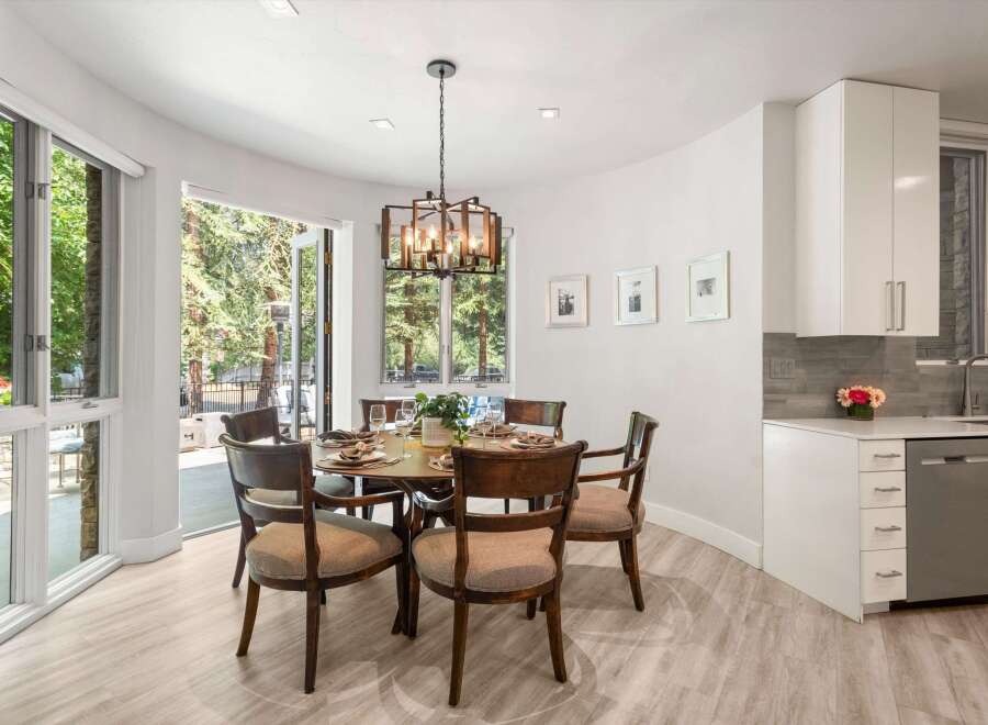 Experience seamless indoor-outdoor living with this elegant dining area, featuring large glass doors that open to a lush, tree-filled patio.