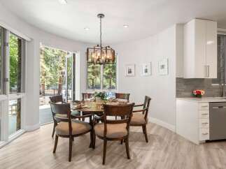 Experience seamless indoor-outdoor living with this elegant dining area, featuring large glass doors that open to a lush, tree-filled patio.