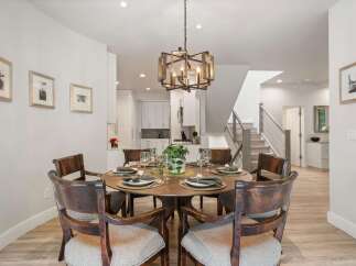 This elegant dining room features a round wooden table set for six, perfect for intimate gatherings.
