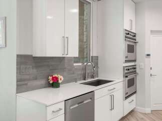 This modern kitchen features sleek white cabinetry and a stylish grey tiled backsplash.
