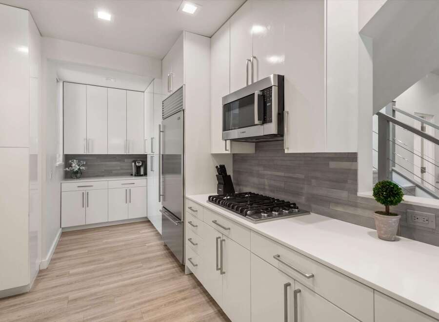 Experience modern living in this sleek kitchen featuring high-gloss white cabinetry and stainless steel appliances.