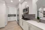 Experience modern living in this sleek kitchen featuring high-gloss white cabinetry and stainless steel appliances.