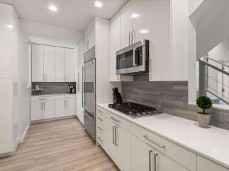 Experience modern living in this sleek kitchen featuring high-gloss white cabinetry and stainless steel appliances.