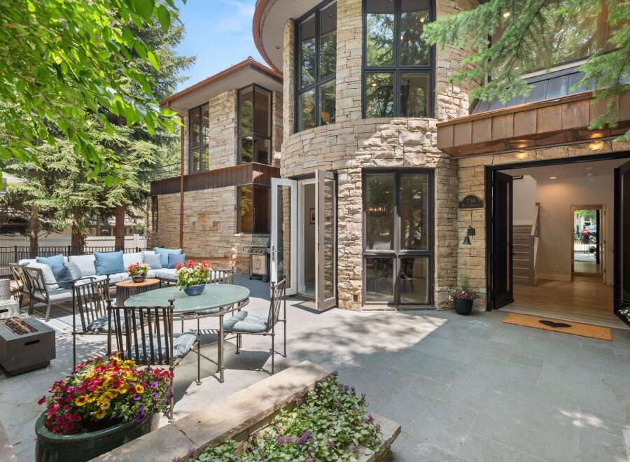 Experience luxurious outdoor living with this stunning patio featuring a comfortable sectional sofa, dining set, and a modern fire pit.