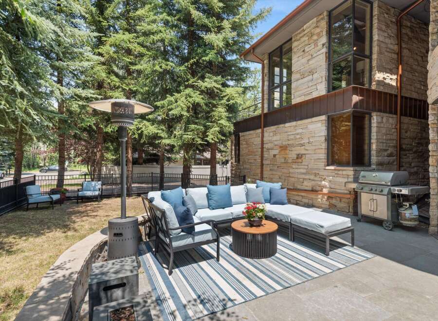 Enjoy outdoor living with this spacious patio featuring a comfortable sectional sofa, a round coffee table, and a propane heater for cooler evenings.