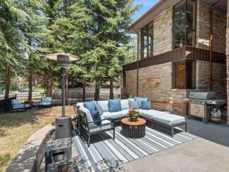 Enjoy outdoor living with this spacious patio featuring a comfortable sectional sofa, a round coffee table, and a propane heater for cooler evenings.