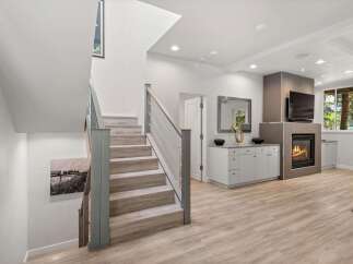 Step into this beautifully renovated home featuring a modern open-concept living space with a cozy fireplace and a sleek entertainment center.