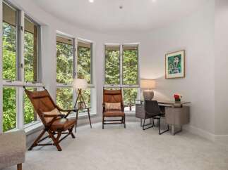 This bright and airy room features large bay windows offering stunning views of the surrounding trees.
