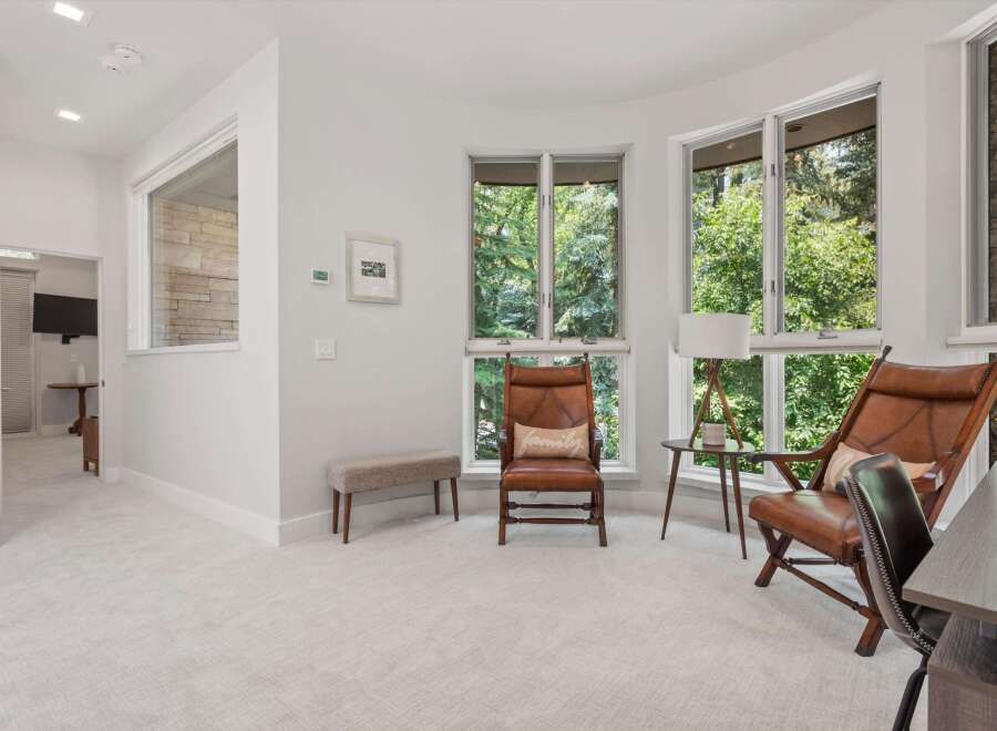 Experience natural light and serene views in this inviting room, featuring large windows that overlook lush greenery.