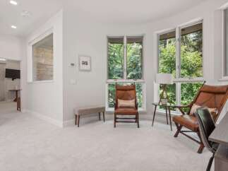 Experience natural light and serene views in this inviting room, featuring large windows that overlook lush greenery.