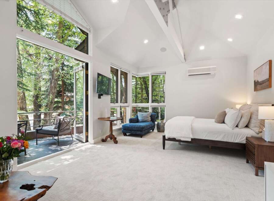 Experience serene living in this luxurious bedroom featuring a spacious king-sized bed and a comfortable chaise lounge, perfect for relaxation.