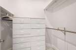 Discover ample storage solutions in this spacious walk-in closet, featuring a sleek white dresser with multiple drawers and a convenient hanging rod.