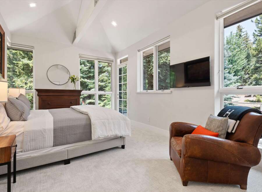 Experience serene living in this beautifully appointed bedroom, featuring a comfortable bed, a cozy leather armchair, and a wall-mounted TV for entertainment.
