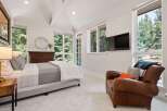 Experience serene living in this beautifully appointed bedroom, featuring a comfortable bed, a cozy leather armchair, and a wall-mounted TV for entertainment.