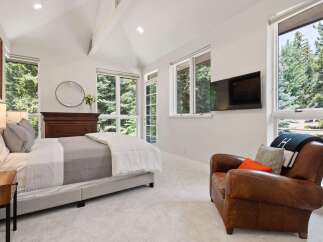Experience serene living in this beautifully appointed bedroom, featuring a comfortable bed, a cozy leather armchair, and a wall-mounted TV for entertainment.