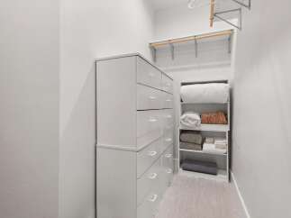 Discover ample storage solutions in this well-organized closet, featuring a tall chest of drawers and a dedicated shelving unit.