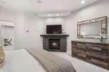 Experience ultimate comfort in this master bedroom, featuring a cozy gas fireplace and a mounted flat-screen TV for entertainment.