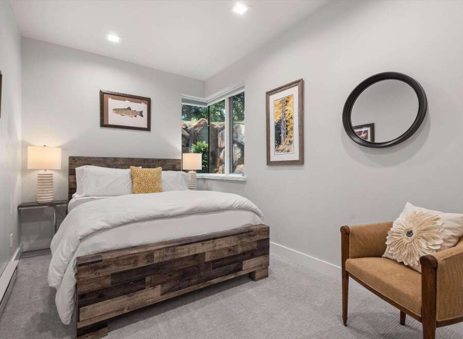 This cozy bedroom features a rustic wooden bed frame complemented by crisp white linens and a decorative yellow accent pillow.