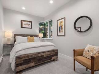 This cozy bedroom features a rustic wooden bed frame complemented by crisp white linens and a decorative yellow accent pillow.