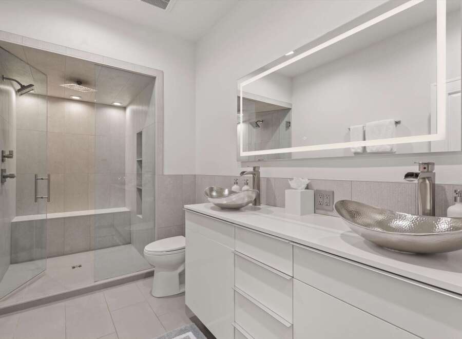 Experience modern luxury in this stunning bathroom, featuring a spacious glass-enclosed shower with multiple showerheads and a built-in bench.