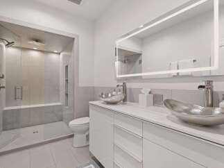Experience modern luxury in this stunning bathroom, featuring a spacious glass-enclosed shower with multiple showerheads and a built-in bench.