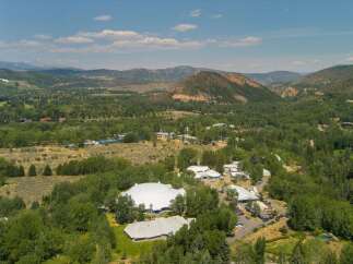 Discover this expansive property nestled in a picturesque valley, featuring a striking white domed structure and multiple modern buildings.
