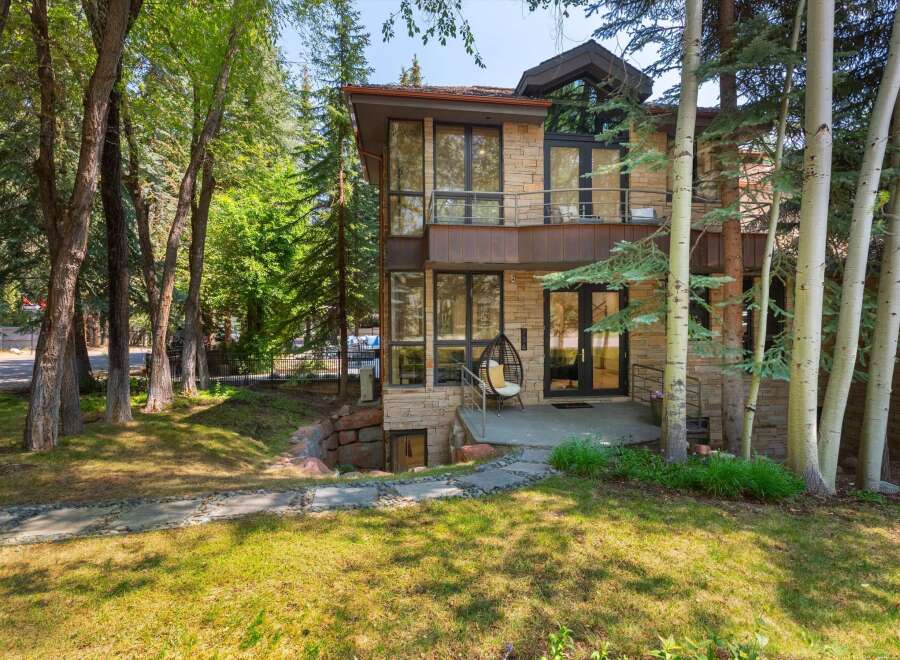 Experience modern mountain living in this stunning home, featuring a striking stone facade and expansive glass windows that invite the natural surroundings indoors.