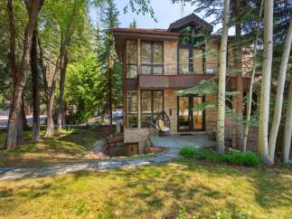 Experience modern mountain living in this stunning home, featuring a striking stone facade and expansive glass windows that invite the natural surroundings indoors.