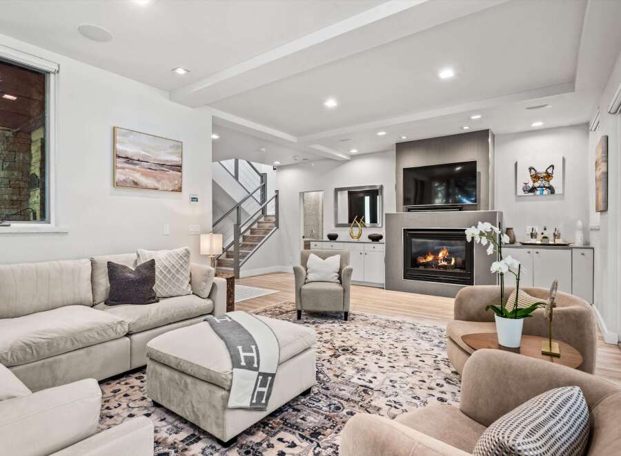 Experience modern luxury in this stunning living room, featuring a cozy fireplace and a large sectional sofa perfect for gatherings.