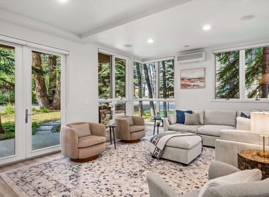 Experience seamless indoor-outdoor living in this beautifully appointed living room, featuring expansive windows and glass doors that invite the serene natural surroundings inside.