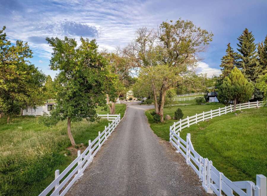 Discover this stunning property featuring a long, tree-lined gravel driveway leading to a beautiful home.
