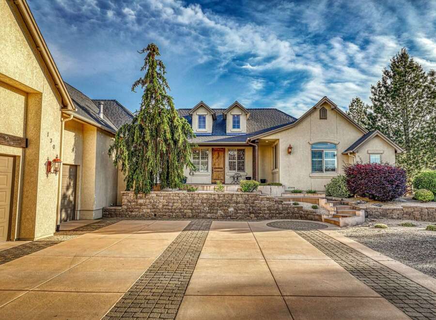 Discover this charming home featuring a welcoming facade with a stone retaining wall and a beautifully landscaped yard.