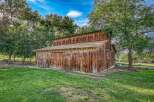 Discover rustic charm with this classic wooden barn, nestled amongst mature trees.
