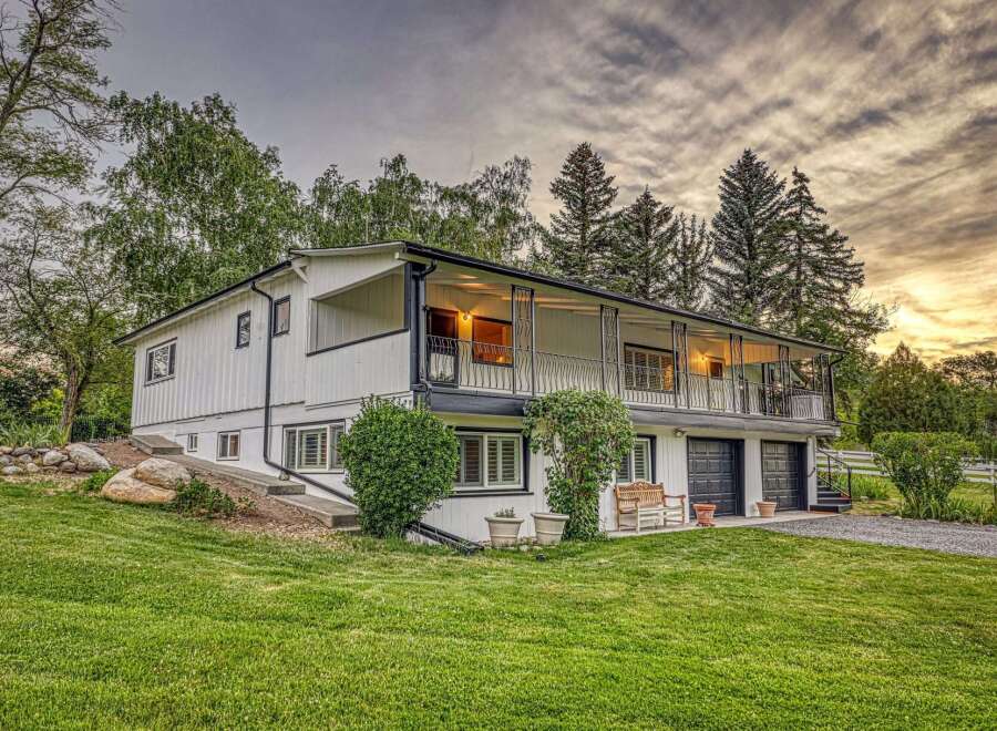 Discover this charming white home featuring a spacious wrap-around balcony perfect for enjoying the serene surroundings.
