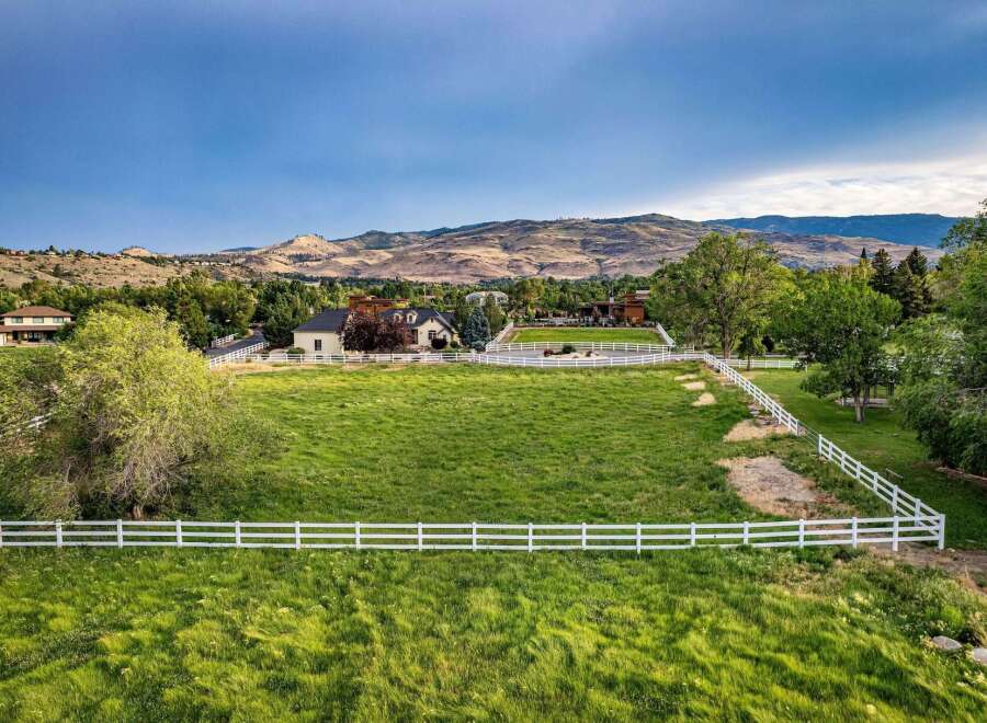 Discover this stunning property featuring a sprawling green lawn enclosed by a pristine white fence, offering a picturesque setting for outdoor activities.