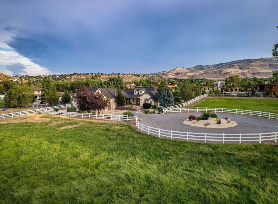 Experience luxury living in this stunning estate, featuring a beautiful home with a circular driveway and pristine white fencing.
