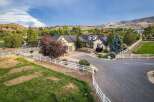 Discover this stunning property featuring a charming cream-colored home with a dark roof, nestled amidst lush greenery and rolling hills.