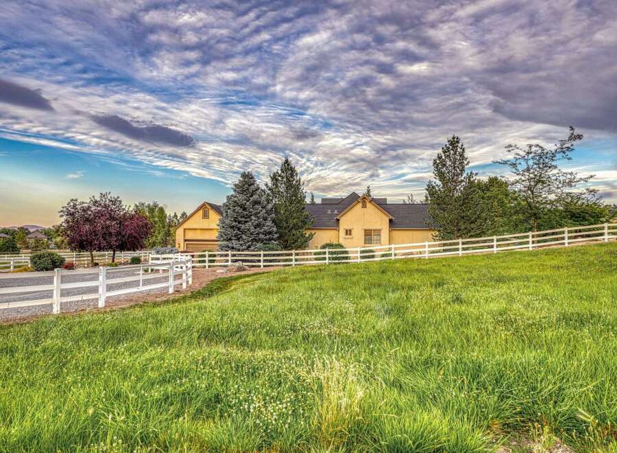 Discover this stunning property featuring a beautiful yellow house with a dark roof, surrounded by lush green grass and mature trees.