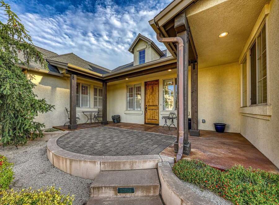 Welcome guests to this charming home with a welcoming courtyard entrance featuring a paved patio and comfortable seating areas.