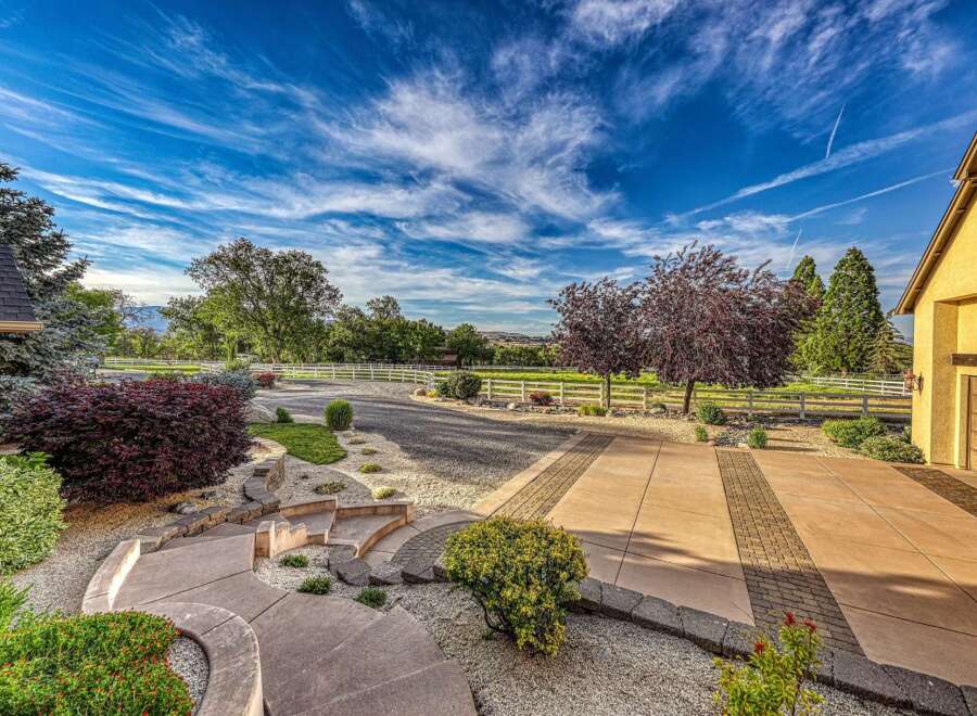 Discover this stunning property featuring a beautifully landscaped entrance with a winding walkway and stone steps, leading to a spacious driveway.
