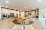 This spacious kitchen boasts custom cream-colored cabinetry with glass-front upper cabinets, complemented by a large butcher block island with a sink.