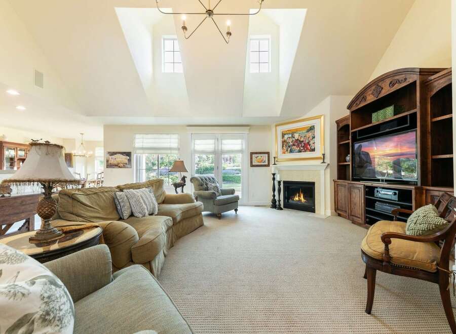 Experience luxury living in this spacious great room, featuring a grand fireplace and a vaulted ceiling with skylights.