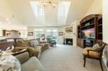 Experience luxury living in this spacious great room, featuring a grand fireplace and a vaulted ceiling with skylights.